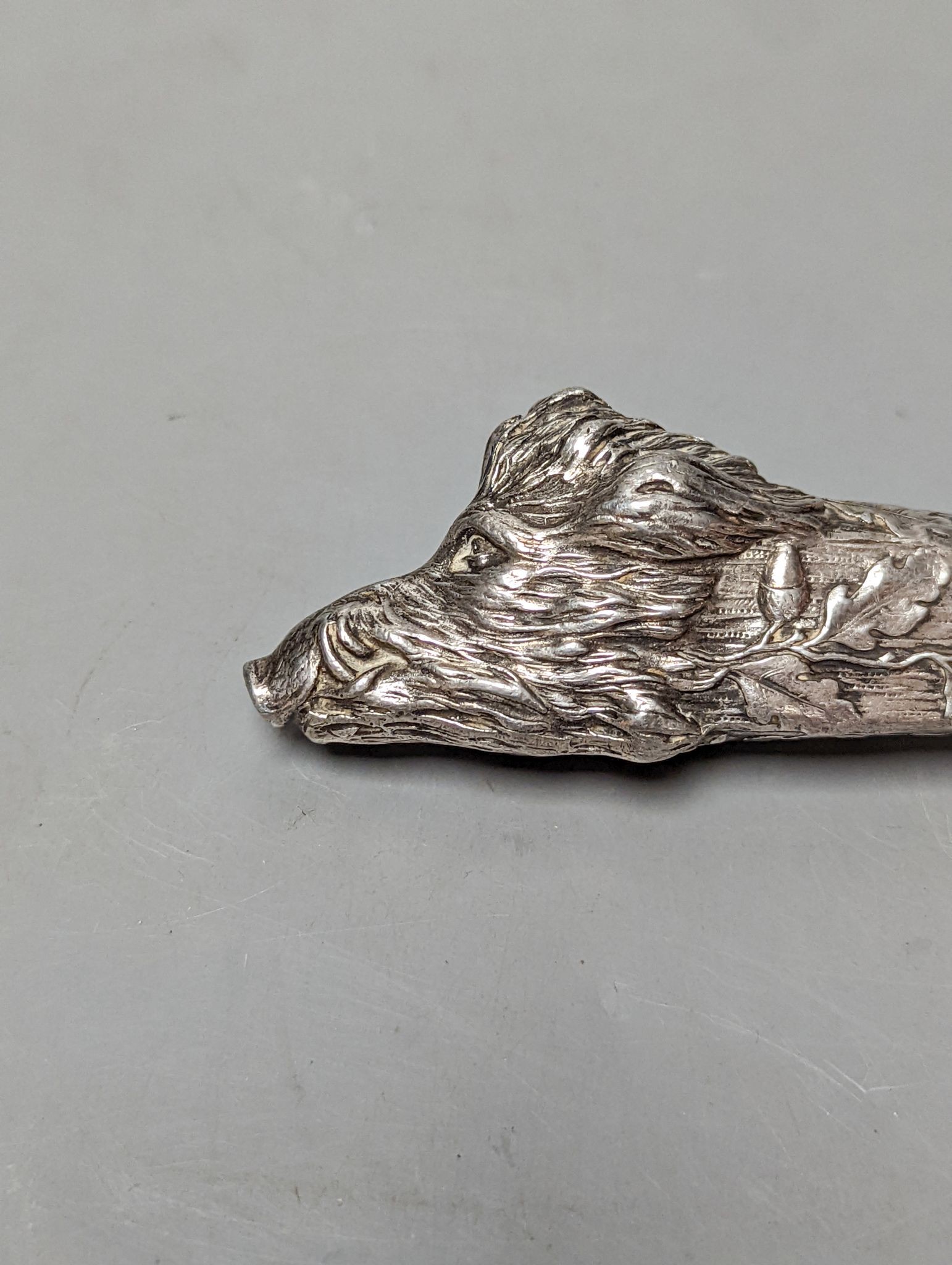 An Austro Hungarian white metal mounted cigar cutter, modelled as the head of a wild boar with acorn leaves, 13.9cm.